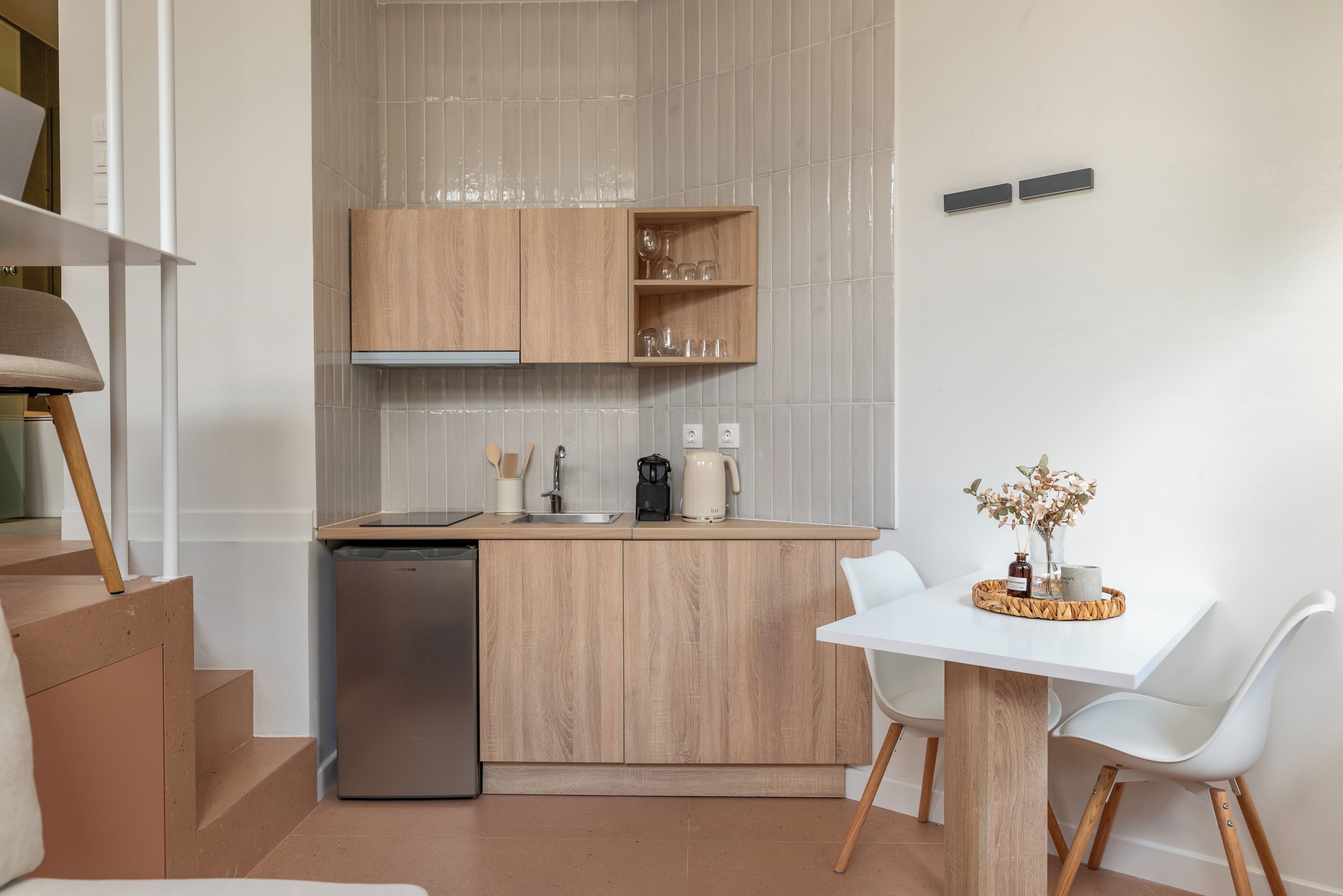 A modern kitchen with wooden cabinets, a dishwasher, and a dining area with a white table and chairs.