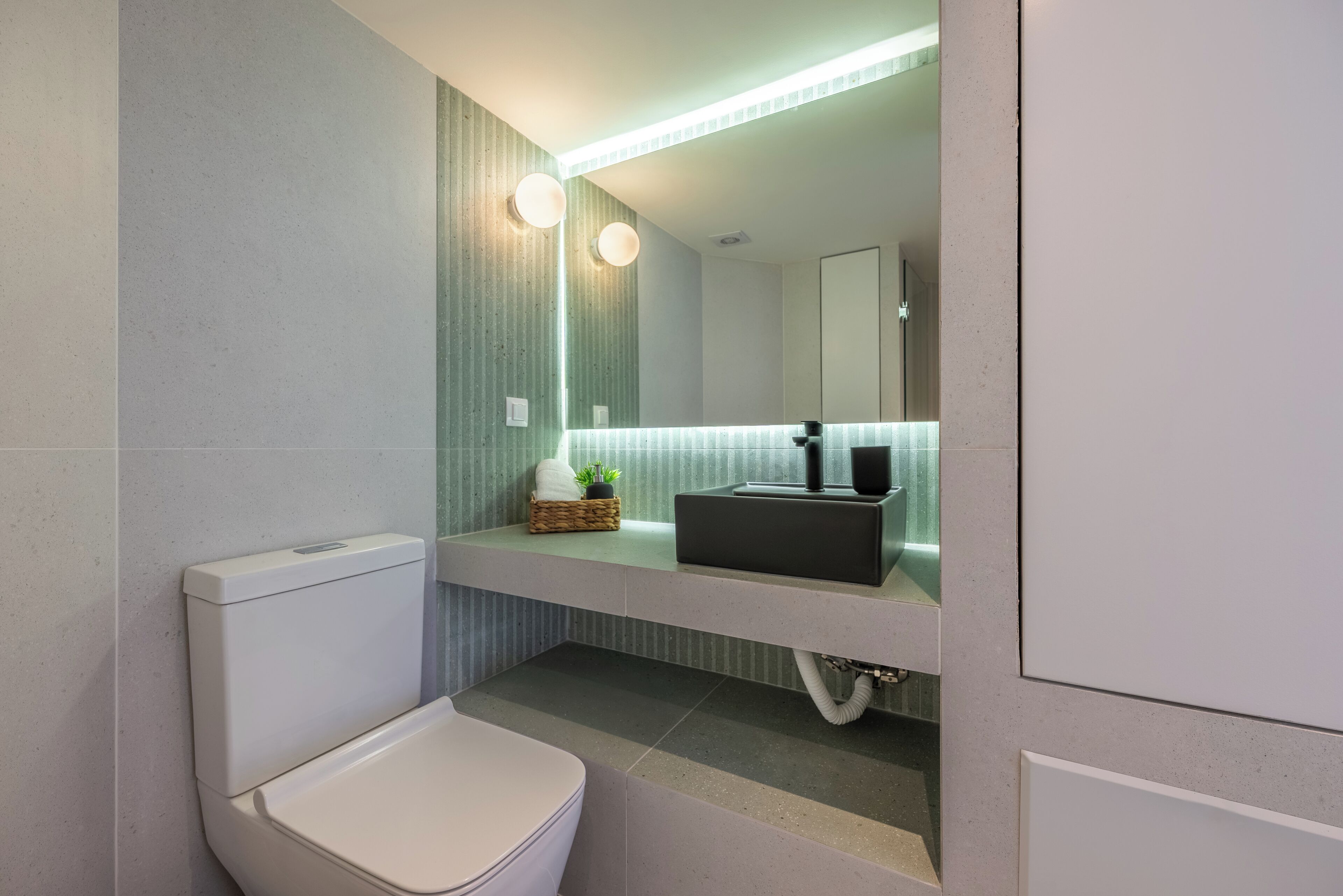 Une salle de bain moderne équipée de toilettes, d’un lavabo et d’un miroir.