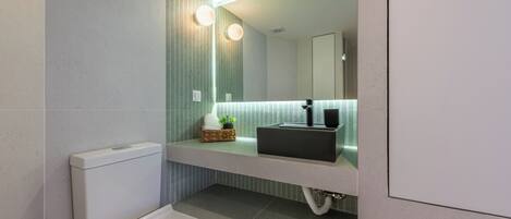A modern bathroom with a toilet, a sink, and a mirror.
