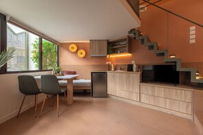 A modern kitchen with a dining area, a built-in TV, and a staircase. - Boutique Studios Psyrri (Athens)