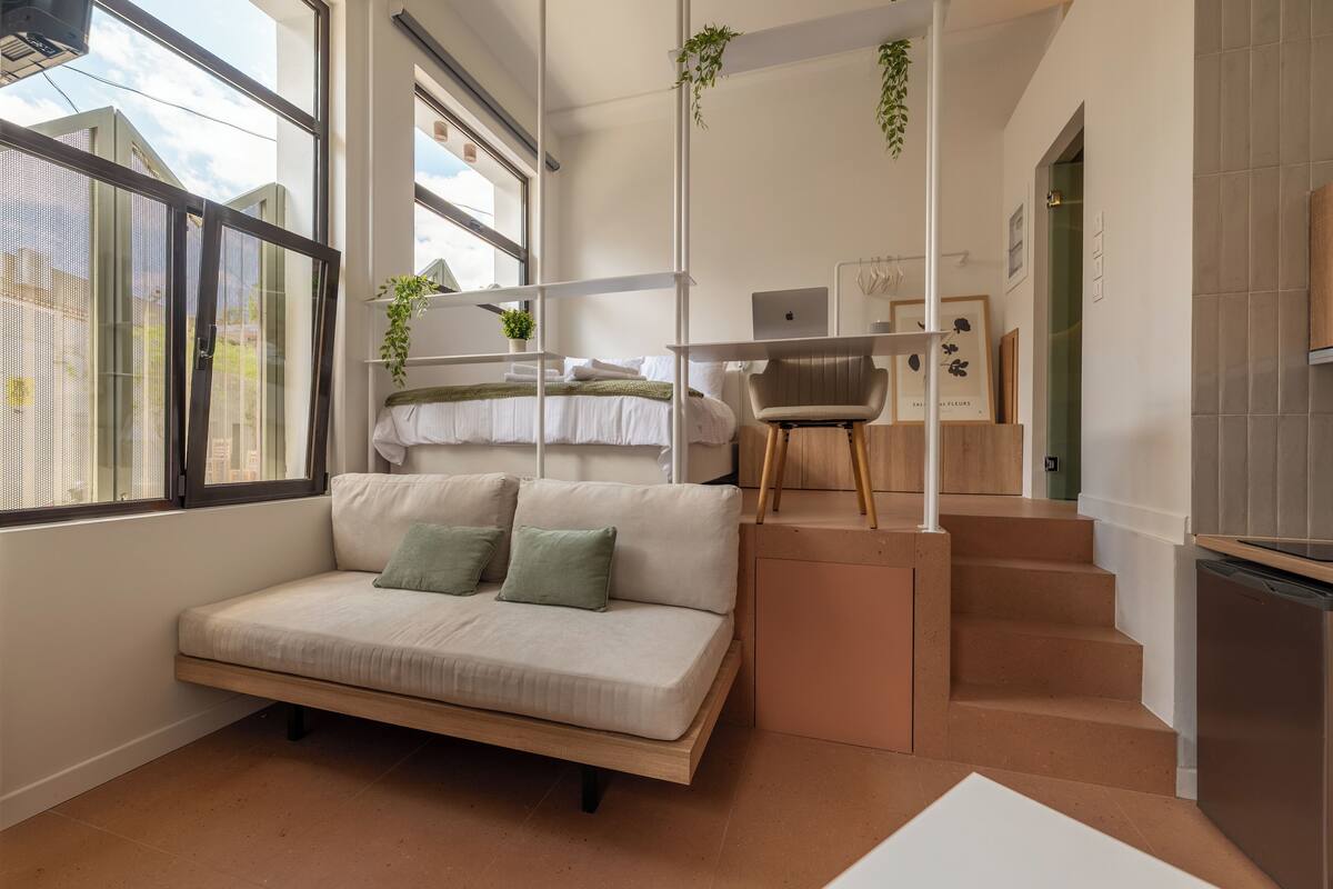 Un espace de vie moderne et compact, comprenant un canapé, un bureau et un escalier.