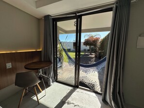 A modern room with a sliding glass door leading to an outdoor area with a hammock and a tree. - Parador Casa da Praia (Torres)