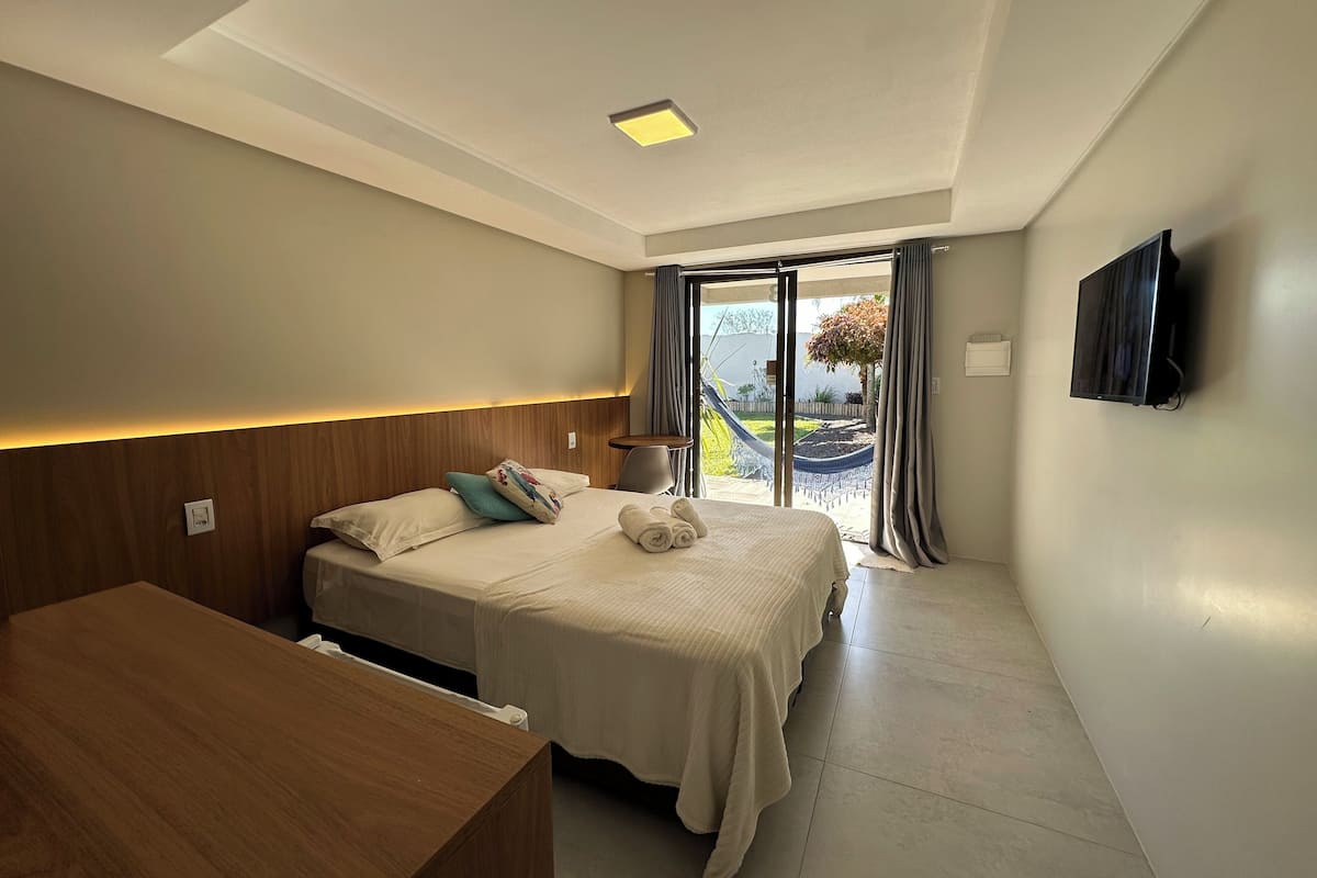 Una habitación de hotel moderna con una cama, una mesita de noche y un televisor fijado a la pared.