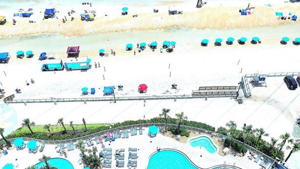 A resort with a large pool, beach area, and lounge chairs.