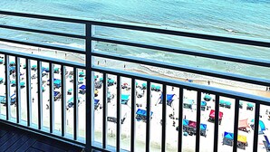 A balcony with a view of the beach and ocean.