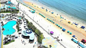 A resort with multiple swimming pools, beach areas, and beach umbrellas.