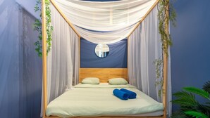 Ein Bett mit Baldachin, ein runder Spiegel darüber und ein blaues Handtuch auf dem Bett.