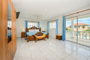 A bedroom with a bed, bedside tables, a wardrobe, a balcony with a view of buildings.