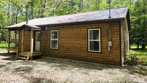 A small wooden cabin with a porch, a door, and two windows.
