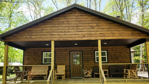 A wooden cabin with a porch, a door, and windows.