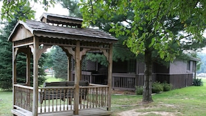A wooden gazebo with a bench, surrounded by a wooden deck and a fence. - Cozy Sugar Pine Cottage (Vowinckel)