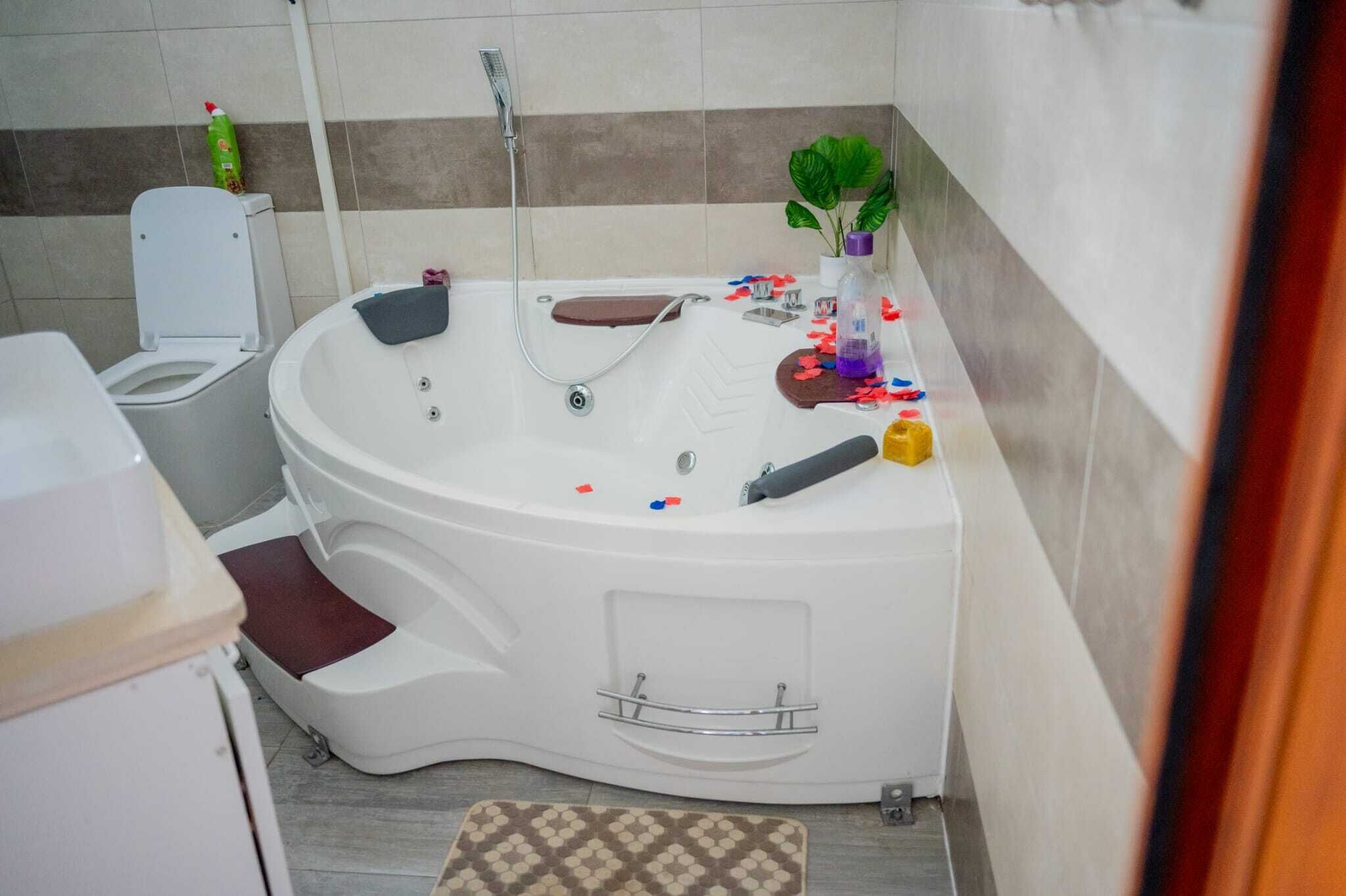 Ein Badezimmer mit Badewanne, Toilette, Dusche und einem kleinen Topfpflanzen.