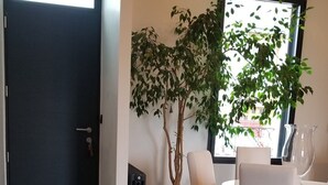 Et moderne spiseområde med et bord, stole, en potteplante og et mønstret gulv.
