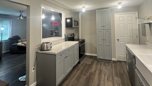 Una cocina moderna con gabinetes grises, una isla central y un microondas integrado.