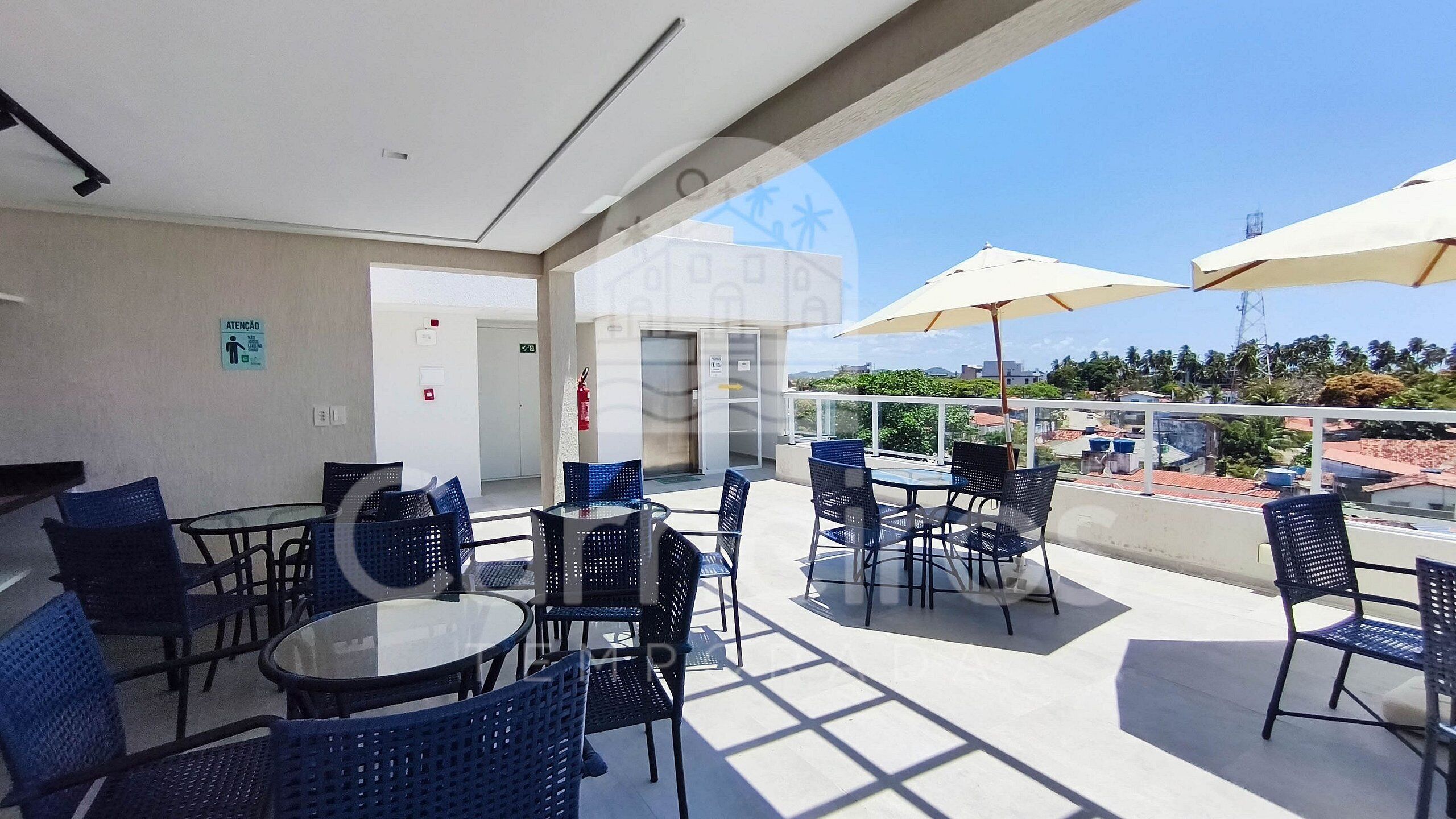 A rooftop terrace with outdoor seating, a fire extinguisher, and a view of the cityscape.