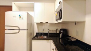 A compact kitchen with a refrigerator, microwave, sink, and coffee maker.