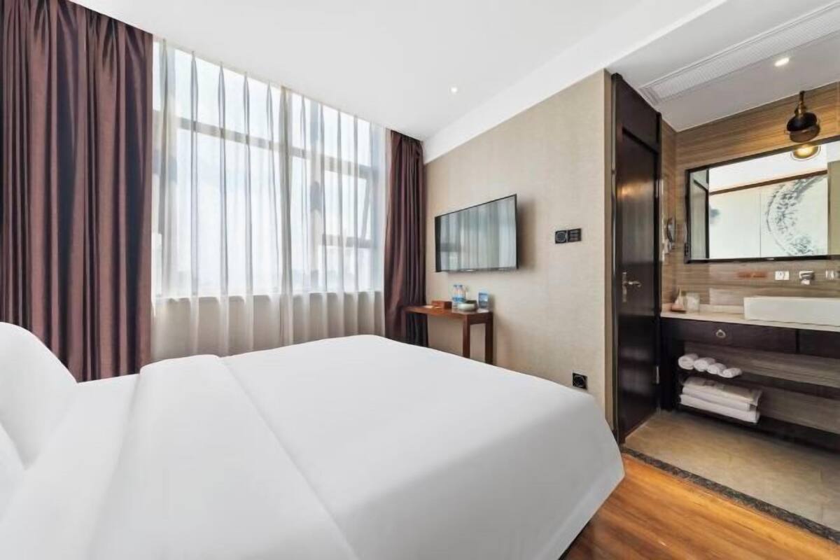Habitació d'hotel amb llit, televisió, bany amb rentapla i mirall, i terra de fusta.