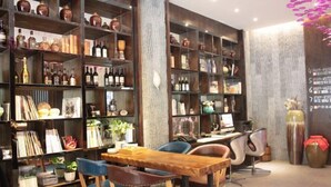A room with wooden bookshelves filled with books and decorative items, a wooden table with chairs, and a computer desk with a chair. - Luzhou Weiyi Hotel (Luzhou)