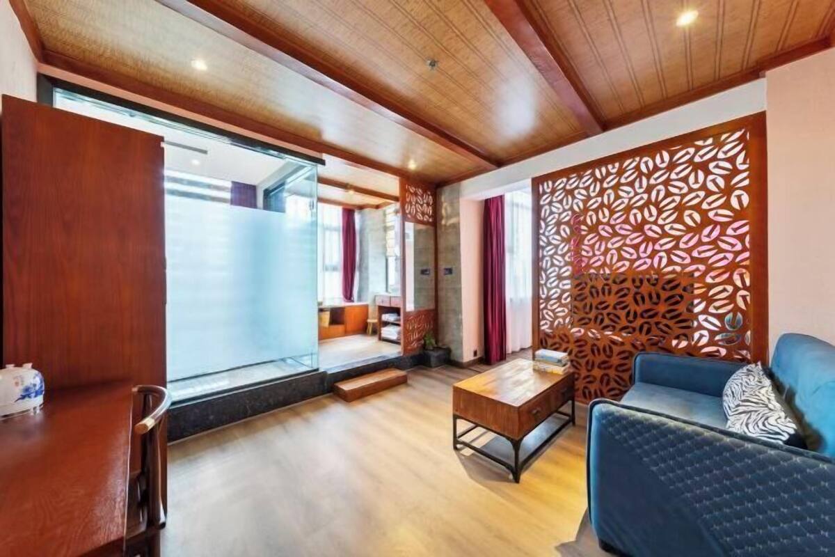 Un interior modern amb sostre de fusta, un sofà blau, una taula baixa de fusta i un panell decoratiu a la paret.