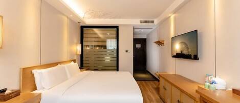 Una habitación de hotel con una cama grande, cabecero de madera, mesitas de noche, un televisor y un armario.