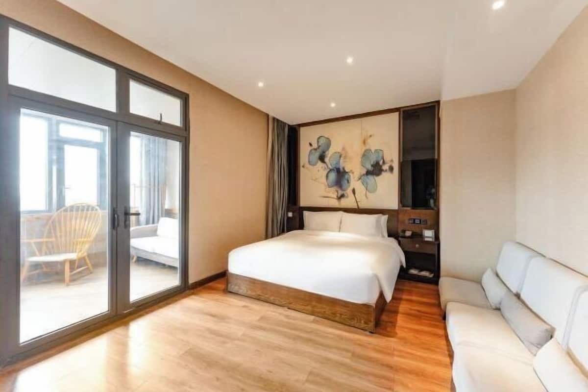 Habitació d'hotel amb un llit gran, un sofà, una televisió i un quadre a la paret.