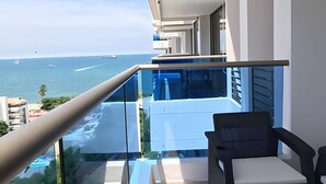Un balcón con vista al mar, una silla y una mesa.