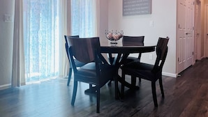 A dining area with a table and chairs, a wall-mounted sign with inspirational quotes, and a door leading to another room. - Bright Modern Retreat Near DIA & Gaylord Resort (Denver)