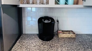 A kitchen with a coffee maker, granite countertop, white cabinets, and a built-in trash can. - Bright Modern Retreat Near DIA & Gaylord Resort (Denver)