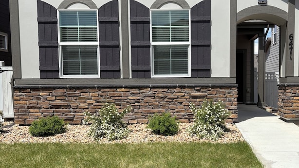 A house with a stone foundation, two windows with shutters, and a well-maintained lawn. - Bright Modern Retreat Near DIA & Gaylord Resort (Denver)