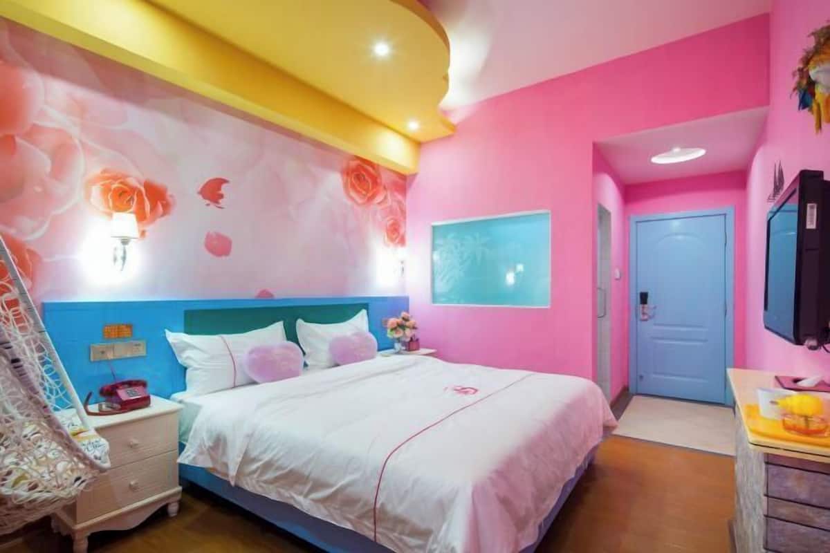 A bedroom with a bed, nightstand, and a wall with floral wallpaper.