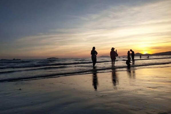 A beach scene with people walking along the shore during sunset. - Sanya Fenglinwan Hotel (Sanya)