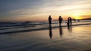 A beach scene with people walking along the shore during sunset. - Sanya Fenglinwan Hotel (Sanya)