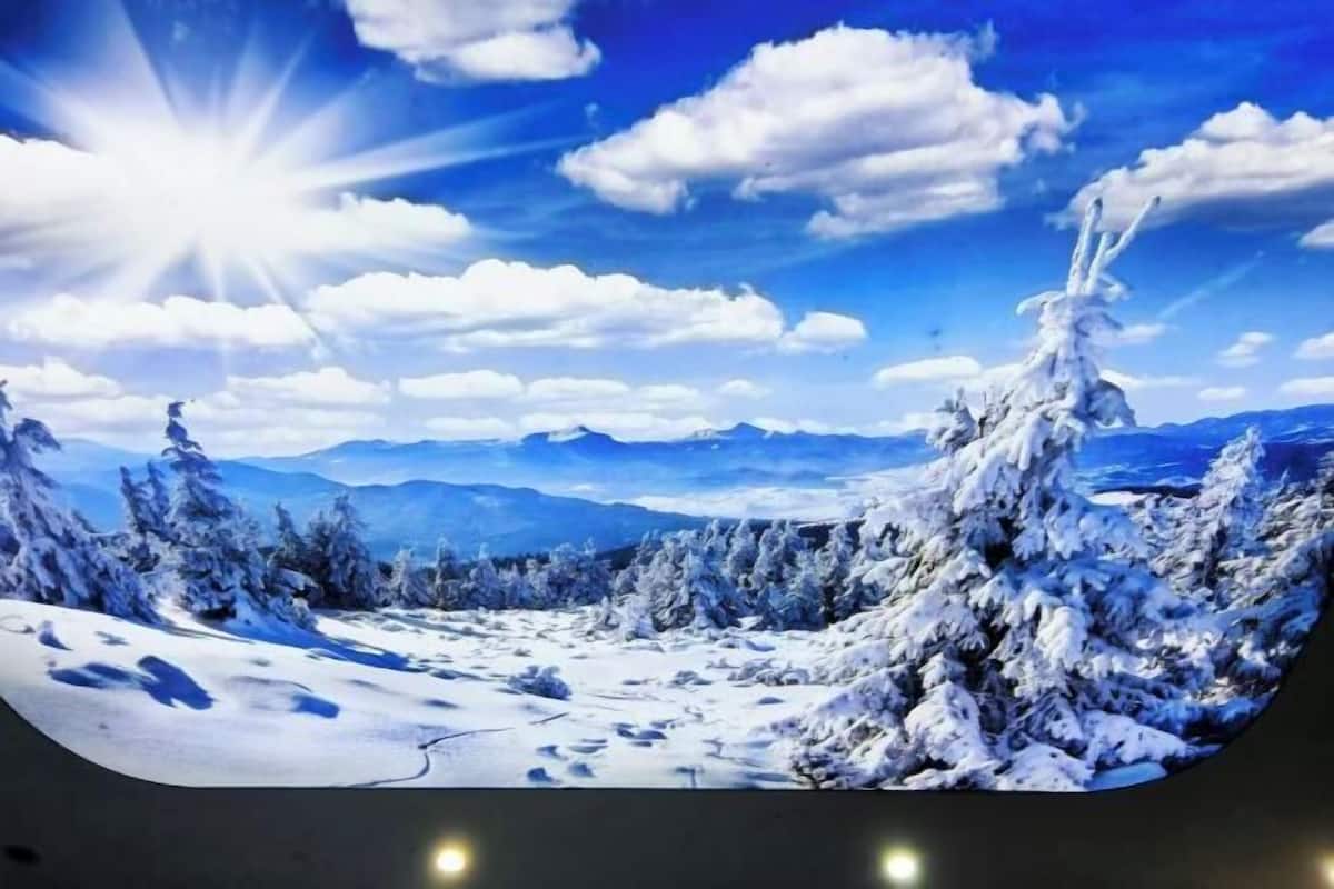 A panoramic view of a snowy landscape with mountains in the background and a clear sky.