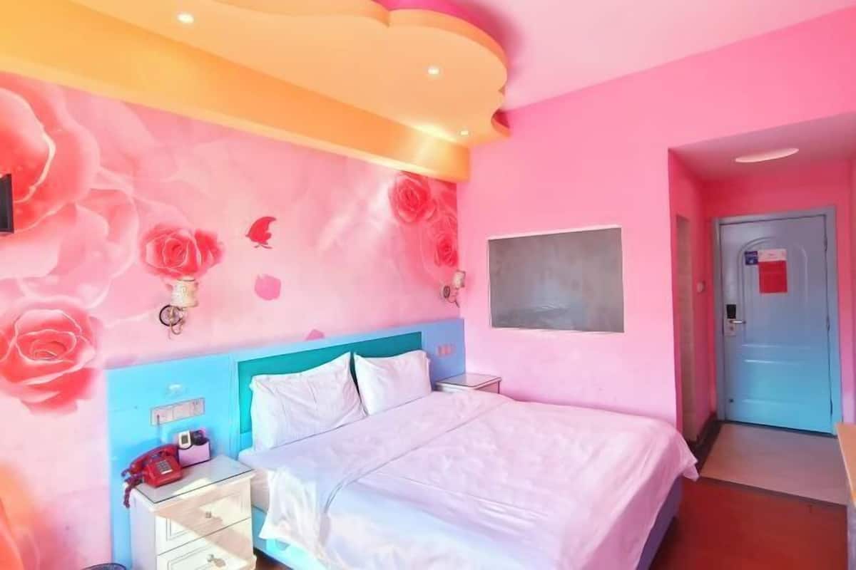 A bedroom with a bed, a nightstand, a wall clock, and a door.