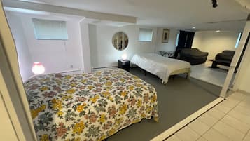 Une chambre à coucher avec une couvre-lit à motifs floraux, un miroir rond, une table de chevet, une chaise et une vue sur un balcon.