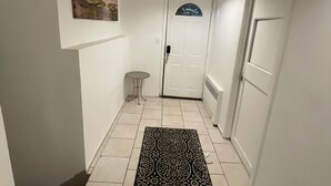 Ein schmaler Flur mit einem gemusterten Teppich, einem kleinen runden Tisch und einer Tür mit Fenster.
