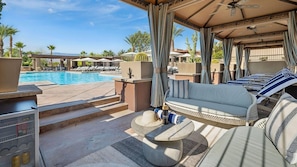 Ein Poolbereich mit Sofa, Sonnenschirm und einer Kühlbox für Getränke.