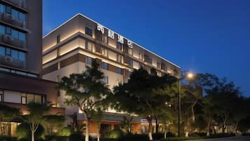A multi-story hotel with a modern design, featuring a prominent entrance and a well-lit facade.
