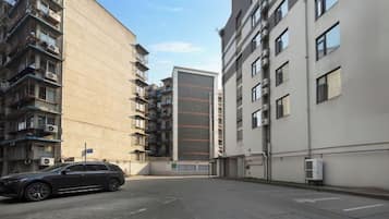 Un edificio residencial de varios pisos con balcones, una zona de estacionamiento y cielo despejado.