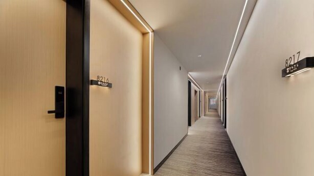 A modern hotel corridor with wooden doors, a carpeted floor, and wall-mounted room numbers. - Xi Ge Hotel (Chengdu)