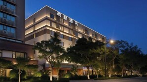 A multi-story hotel with a modern design, featuring balconies and a well-lit facade. - Xi Ge Hotel (Chengdu)