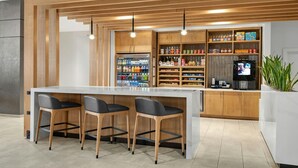 Een moderne keuken met een centraal eiland, barkrukken, houten kastjes en een koelkast.
