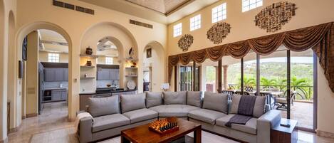 A spacious living area with a large sectional sofa, a wooden coffee table, and a view of the outdoors.