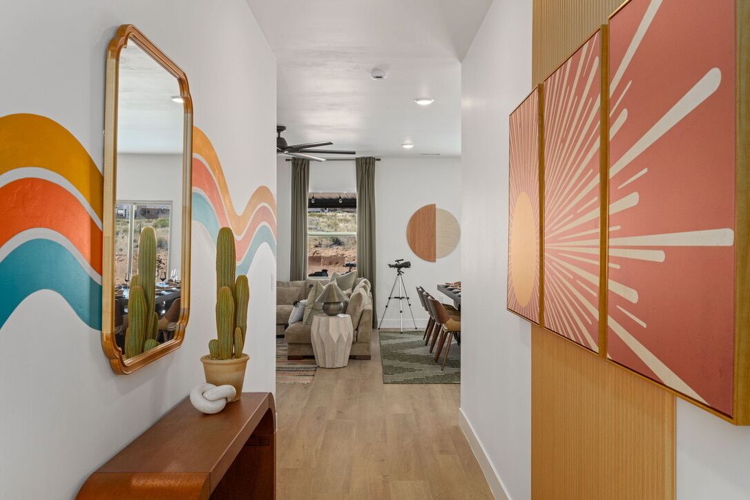 A hallway with a wooden bench, a mirror, and a cactus. There is a dining area with a table and chairs.