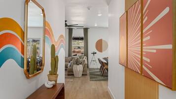 A hallway with a wooden bench, a mirror, and a cactus. There is a dining area with a table and chairs.