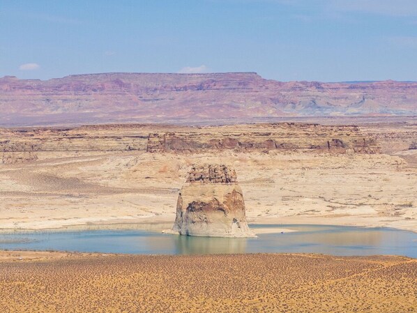 Un paisaje extenso y llano, con una gran formación rocosa en primer plano y una masa de agua.
