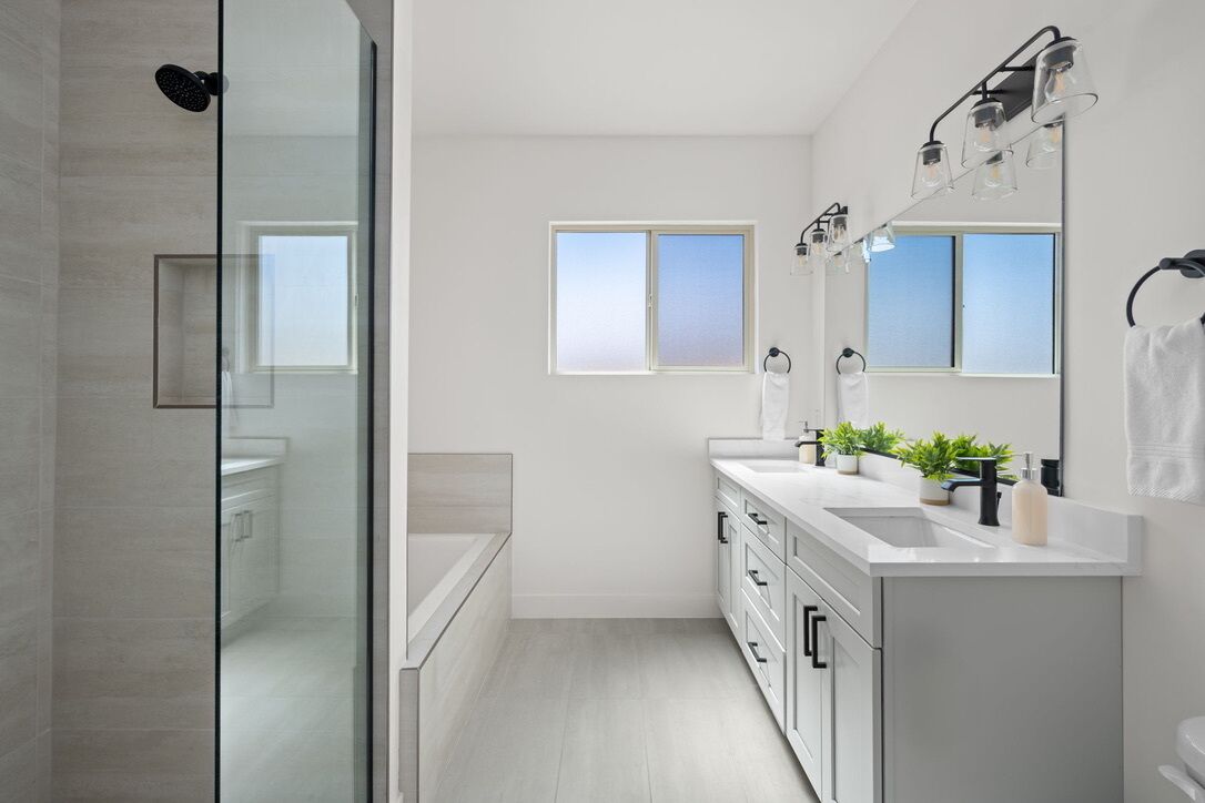 Een moderne badkamer met een douchecabine van glas, een grote spiegel en een raam voor natuurlijk licht.