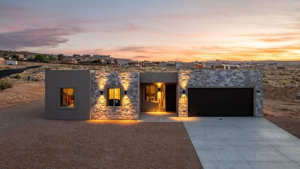 Una casa moderna con fachada de piedra, un garaje y un camino de entrada.