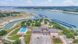 An aerial view of a hotel with a swimming pool, a parking lot, and a dock area with boats. - NEW LISTING! Stunning Lakehouse with Views, Hot Tub & Game Room! (Lago Vista)