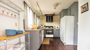 A kitchen with a wooden countertop, stainless steel shelving, a white refrigerator, and a microwave.
